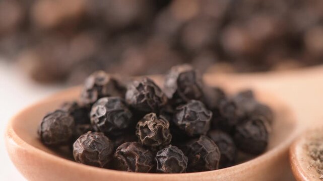 Pile of whole black peppercorns on white background