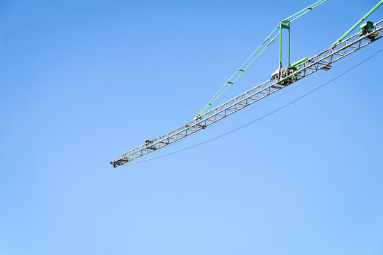 Crane against blue sky. Modern engineering, development and building construction project. Horizontal photo of engineering, transport and heavy lifting at industrial site.