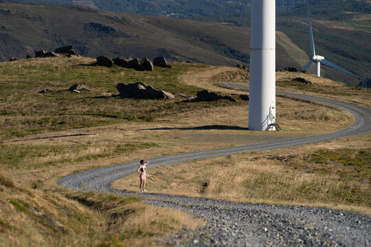 A white woman stands on a gravel path looking
