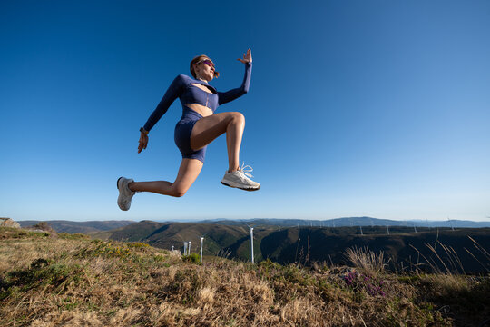White Woman in athletic wear jumping outdoors in the hills of Galicia