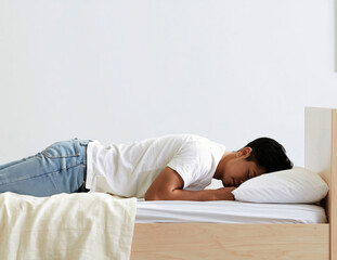 Fototapeta premium young man with black hair lies face down on a bed