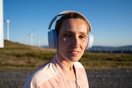 White Woman enjoys music outdoors near wind turbines in Galicia, Spain