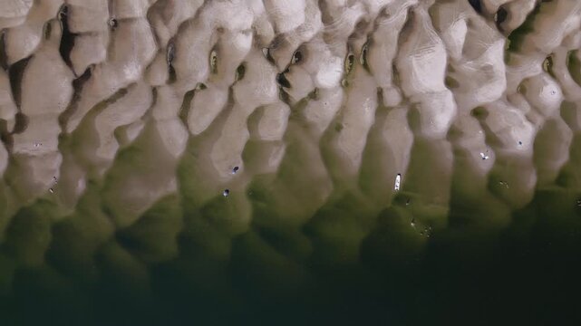 Aerial top-down drone video panning right over exposed sandbars, small boat, and shallow water on Danube River near Apatin, Serbia, showing severe low water levels caused by global climate change.