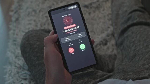 Person holding smartphone with incoming spam call notification, showing suspected spam warning screen, concept of phone scam, cybersecurity and fraud prevention