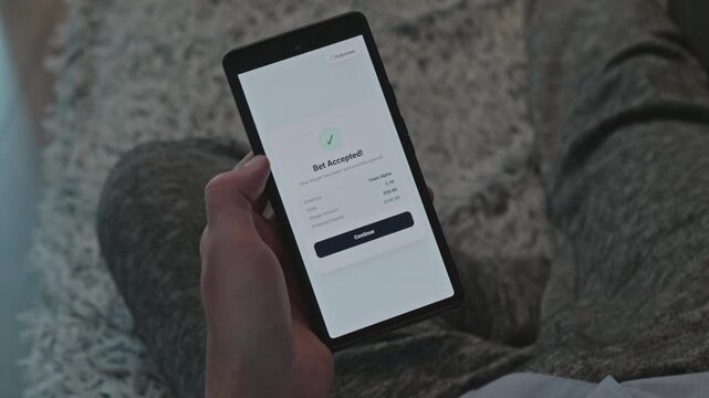 Man Relaxing at Home and Placing Online Sports Bet on Mobile Phone, Successful Wagering Confirmation Screen