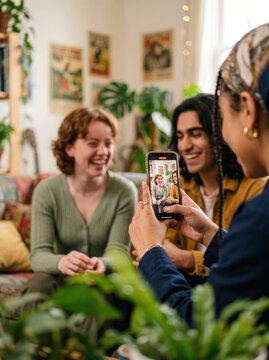Friends take smartphone selfie in cozy plant-filled room
