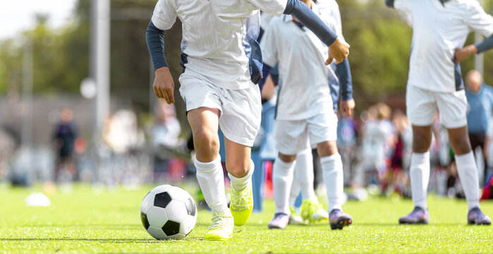Close-Up Action of Junior Soccer Players Dribbling Ball Across Pitch During Training Match - Youth Football Team in White Kits Playing Practice Game