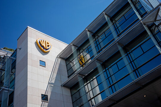 WARSAW, MASOVIAN VOIVODESHIP, POLAND - AUGUST 04, 2026: Exterior view of a modern corporate office building featuring a prominent golden Warner Bros logo.