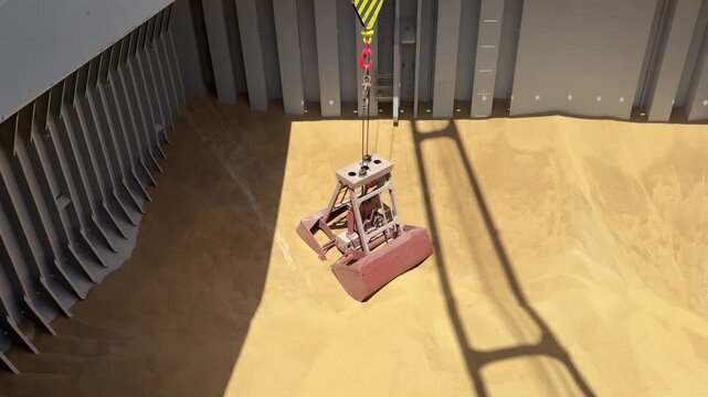 Clamshell bucket crane pick, assemble grain cargo from vessel hold at maritime port terminal, heavy machinery operating bulk cargo transport logistics 