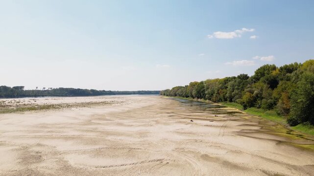 Wide aerial drone video of vast dried Danube riverbed near Apatin, Serbia, showing extensive sandbars and severe water level drop caused by summer drought and global climate change.