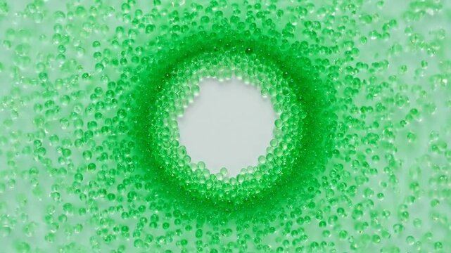 Green beads swirling in circular pattern around central void on light background