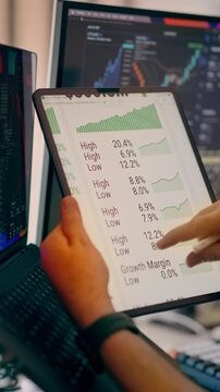 Tablet financial dashboard stock market data interactive analytics display. Close-up of investor hands holding a digital tablet showing real-time growth margin graphs