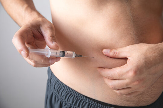 Caucasian man injecting insulin in belly.