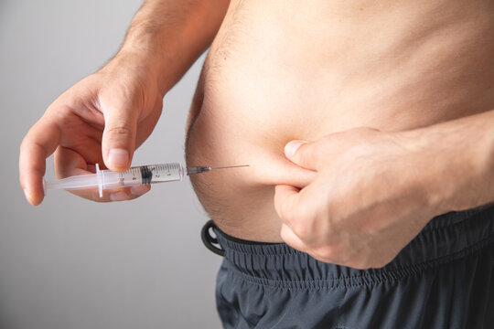 Caucasian man injecting insulin in belly.