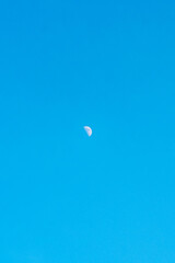 Small crescent moon in a clear bright blue sky, creating a simple minimalist scene with plenty of negative space. © Said21 Photography 
