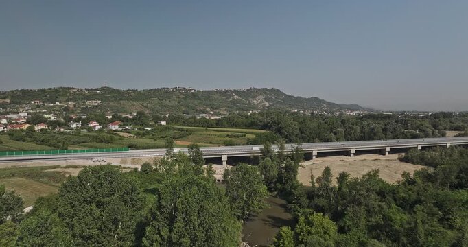 Tirane Albania Aerial v1 low flyover above a river corridor and highway bridge near Nd&euml;rmjet&euml;s, revealing farmland, homes and the surrounding plain - Shot with Mavic 3 Pro Cine - July 10th 2024