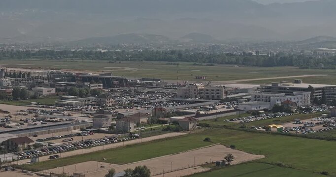 Tirane Albania Aerial v5 telephoto low flyover revealing Tirana International Airport runway, terminal district and car lots across Rinas farmland - Shot with Mavic 3 Pro Cine - July 10th 2024