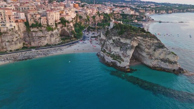 A highangle shot showcasing the historic town of Tropea perched on cliffs above the turquoise Tyrrhenian Sea and the iconic Santa Maria dell Isola monastery.