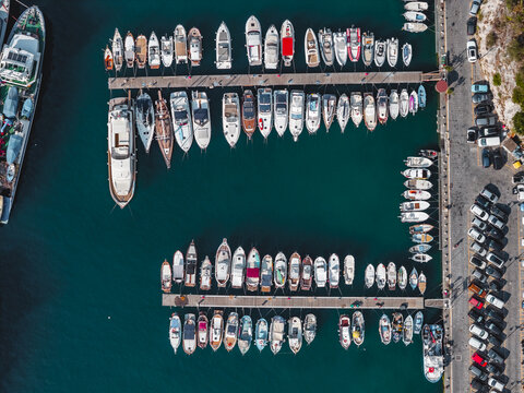 Aerial view of a marina in Cetara filled with numerous yachts and motorboats docked at wooden piers along the coastline of the Amalfi Coast, Campania, Italy.