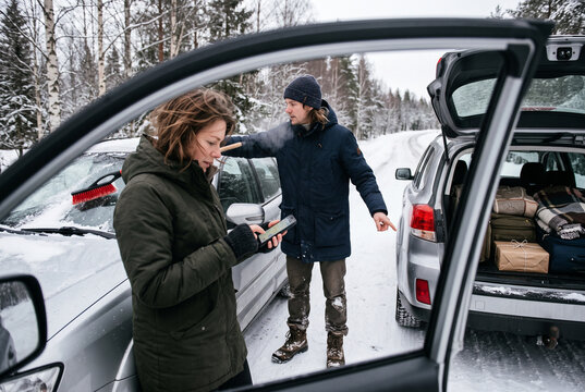 Winter roadside car breakdown scene with couple and open trunk unloading luggage for travel assistance background and banner use