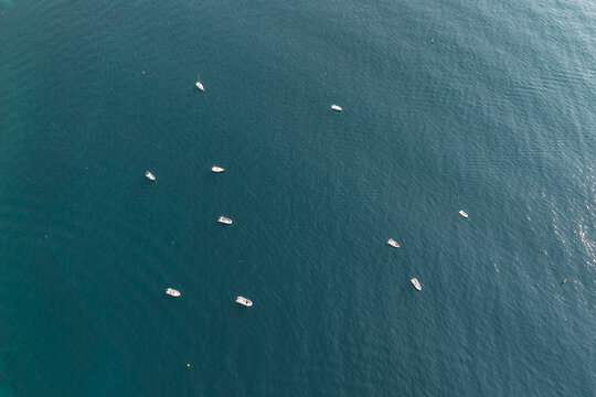 Aerial view of small boats scattered across the deep blue waters of the Tyrrhenian Sea in Cetara, Amalfi Coast, Campania, Italy.