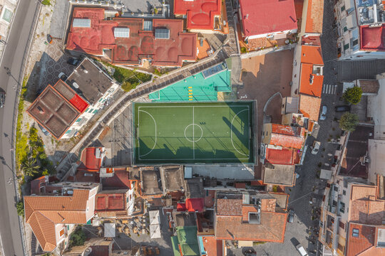 Aerial view of a soccer field nestled among traditional terracotta-roofed buildings and narrow streets in the coastal town of Cetara, Amalfi Coast, Campania, Italy.