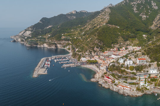 Aerial view of the picturesque coastal village of Cetara with its harbour, fishing boats, and colourful buildings nestled against the steep cliffs of the Amalfi Coast in Cetara, Campania, Italy.