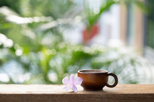Wooden cup and purple orchid flower on wooden table with nature background