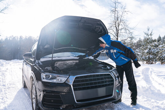 Driver inspect broken car on snowy winter roadside