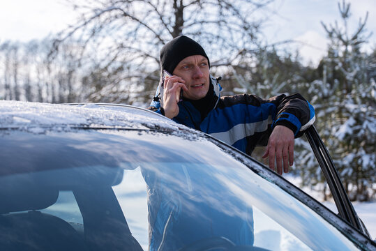Man call roadside assistance beside car in winter