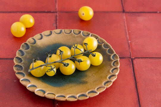 Yellow cherry tomatoes on ceramic plate on red tiles