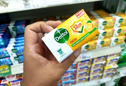 KUALA TERENGGANU, MALAYSIA- AUGUST 06. 2026: Person holding a bar of Dettol Fresh Antibacterial Soap in a yellow wrapper with retail supermarket shelf displays in the background.