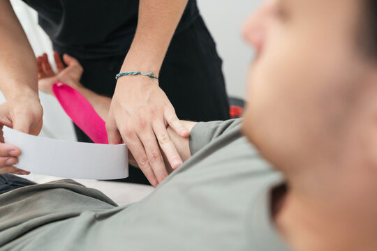 Physical therapist applying kinesiology tape on patient arm