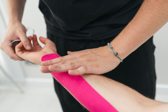Physical therapist applying kinesiology tape on patient wrist