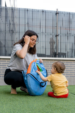 Mother and baby unpack play tent on artificial grass