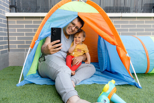 Father take selfie with baby in colorful play tent