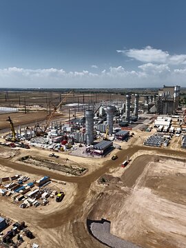 Aerial view of the Fort St. Vrain Generating Station industrial facility showing construction activity with tall chimneys, cranes, and dirt grounds in Platteville, Colorado, United States.