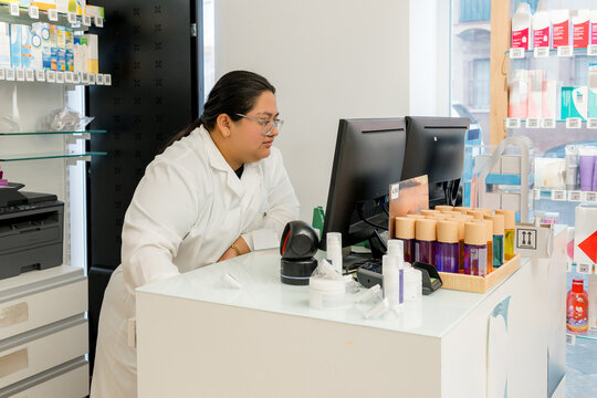 Pharmacist checking computer at pharmacy counter
