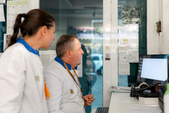 Pharmacists review prescription data on pharmacy computer