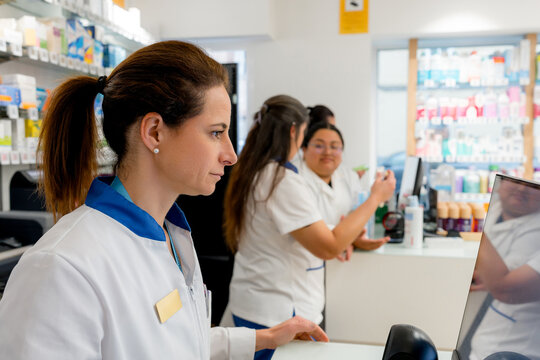Pharmacist at pharmacy counter with medicine shelves