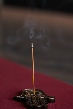Burning incense stick with smoke on decorative holder