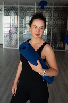 Woman hold yoga mat in fitness studio before training