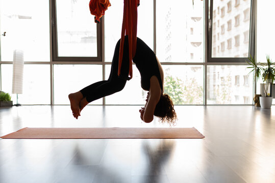 Woman practice aerial yoga exercise in bright studio