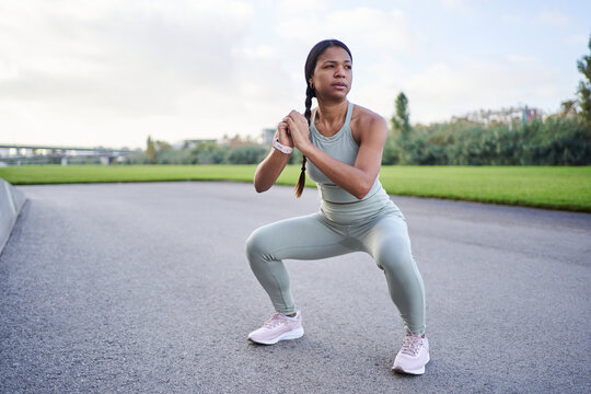 African millennial woman wearing sportswear and training outdoors, performing a fitness workout focused on strength and wellness, representing healthy lifestyle and motivation.
