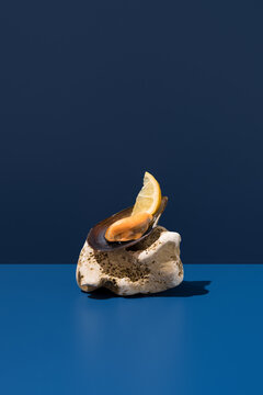Mussel with lemon wedge on coral against blue background