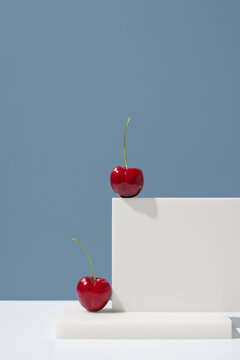 Jerte cherries on white pedestal against blue background