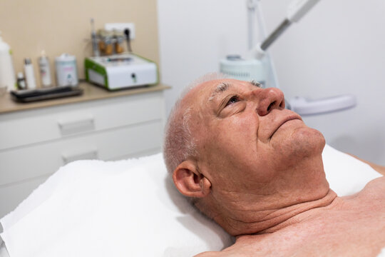 Senior man receiving facial skincare treatment at clinic