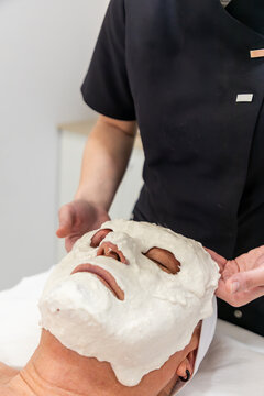 Esthetician remove dried facial mask during skincare treatment