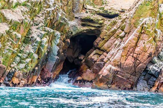 A view from a tourist boat towards a small cave inlet in the Ballestas Islands, Paracas, Peru in the dry season