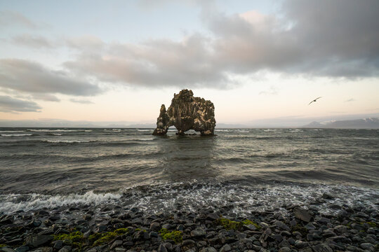 Rock arch on Icelandic coast beneath cloudy sky